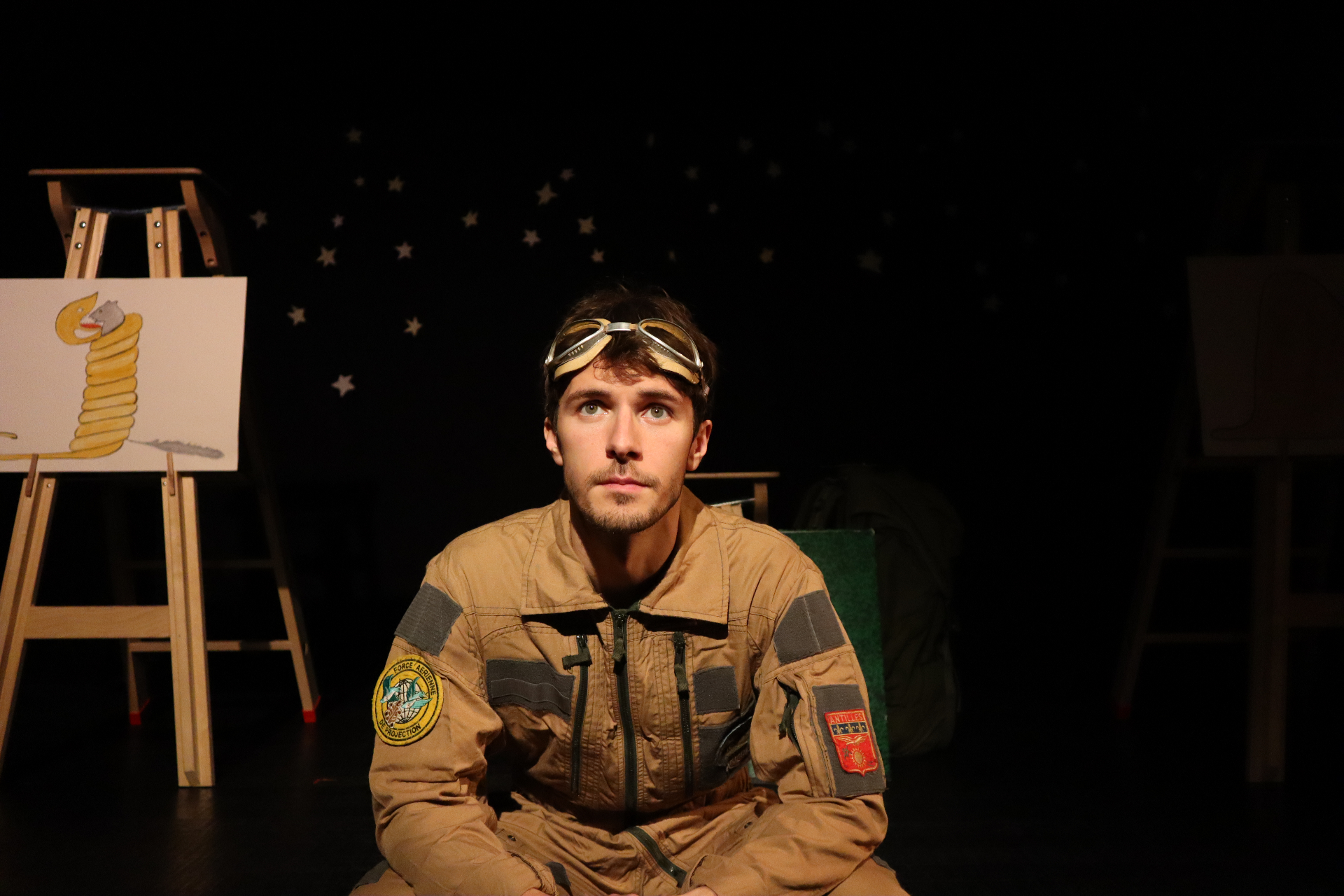 Scène Le Petit Prince - Le Pilote en combinaison sous un ciel étoilé